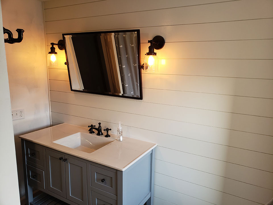 Updated vanity with mirror and fixtures on tile wall