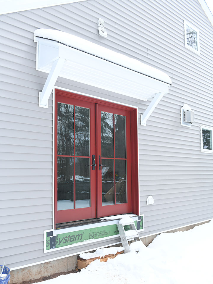 Exterior door replaced with red Marvin French doors on house with gray siding