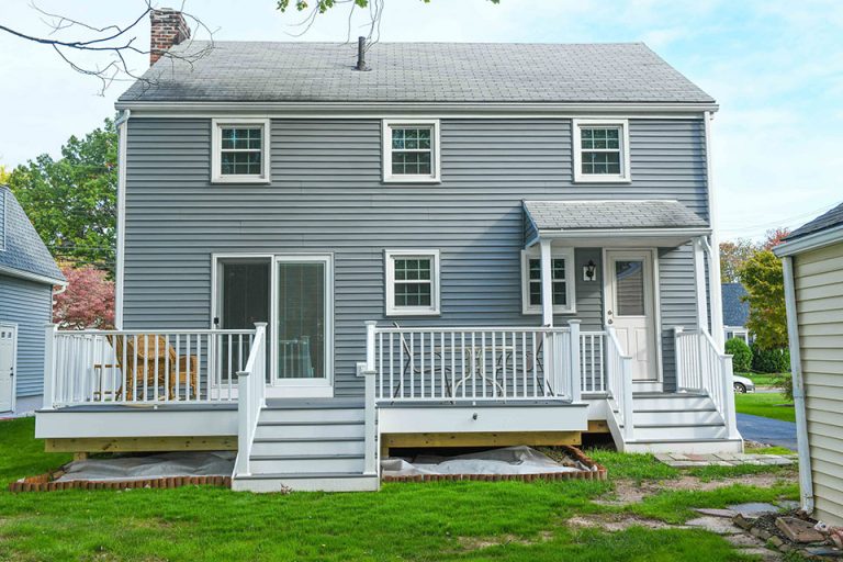 New deck in Pebble Grey color with white railings on house with gray siding.