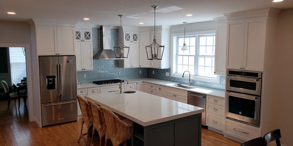 Kitchen renovation in Avon, CT showing center island, white cabinets with blue tile backsplash.