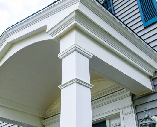 Close up of portico build with white columns on house.